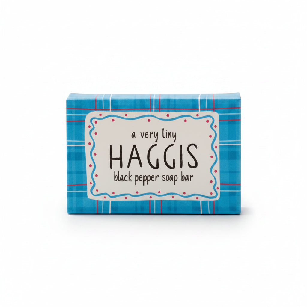 A small rectangular box of Haggis black pepper soap bar, featuring a blue plaid pattern with a white central label that reads 'a very tiny HAGGIS black pepper soap bar'.