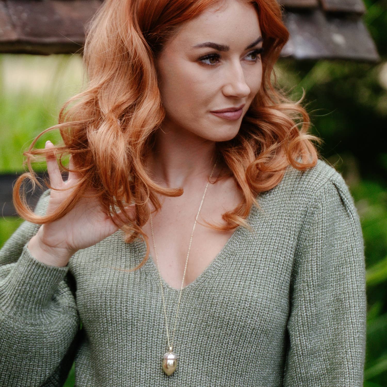Model wearing Bill Skinner Squirrel Acorn Locket with green knit sweater, pendant resting at chest length.