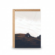 Home in the Borders greeting card featuring illustrated Danish cottage on rolling hills with kraft envelope.
