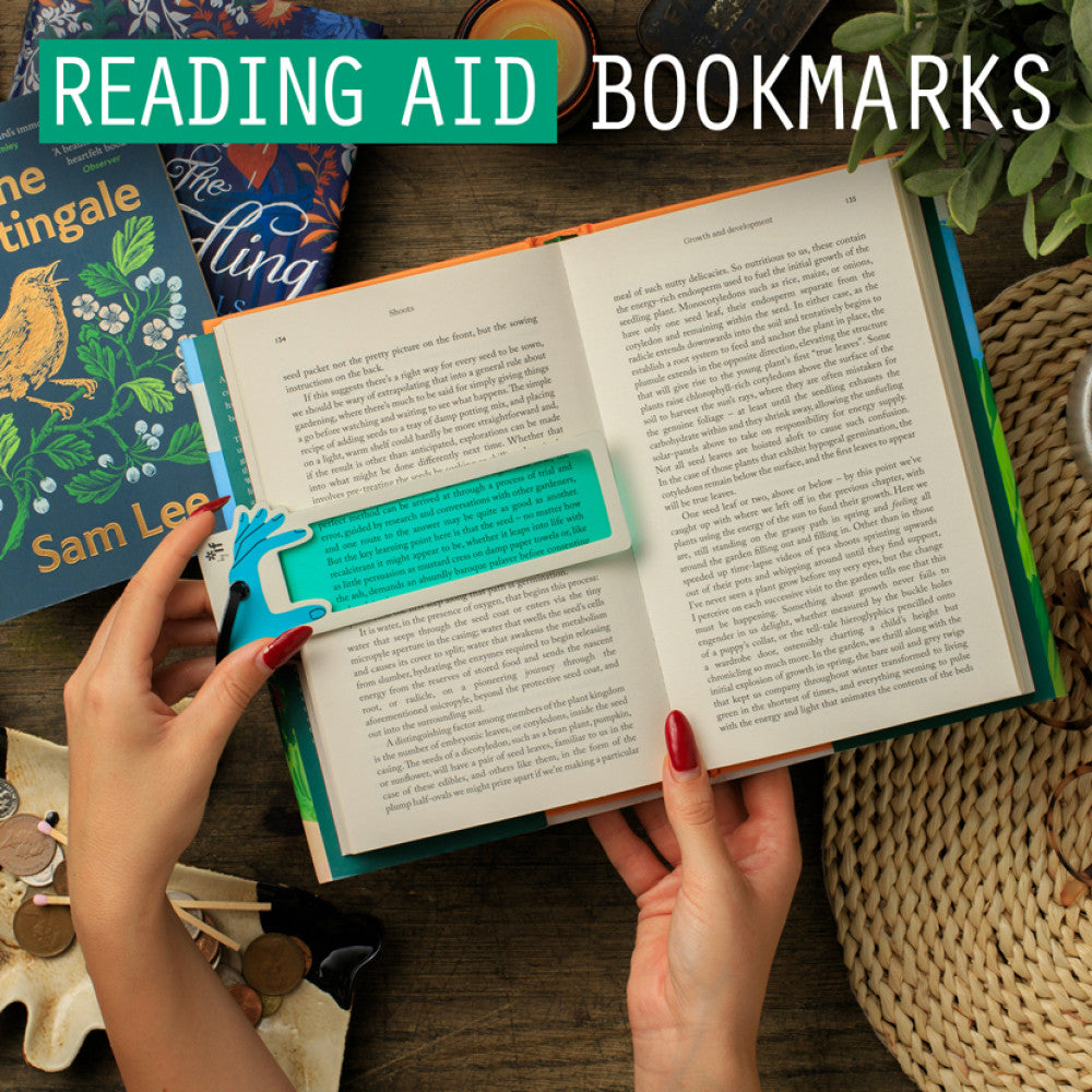 Hands holding an open book with a green reading aid bookmark