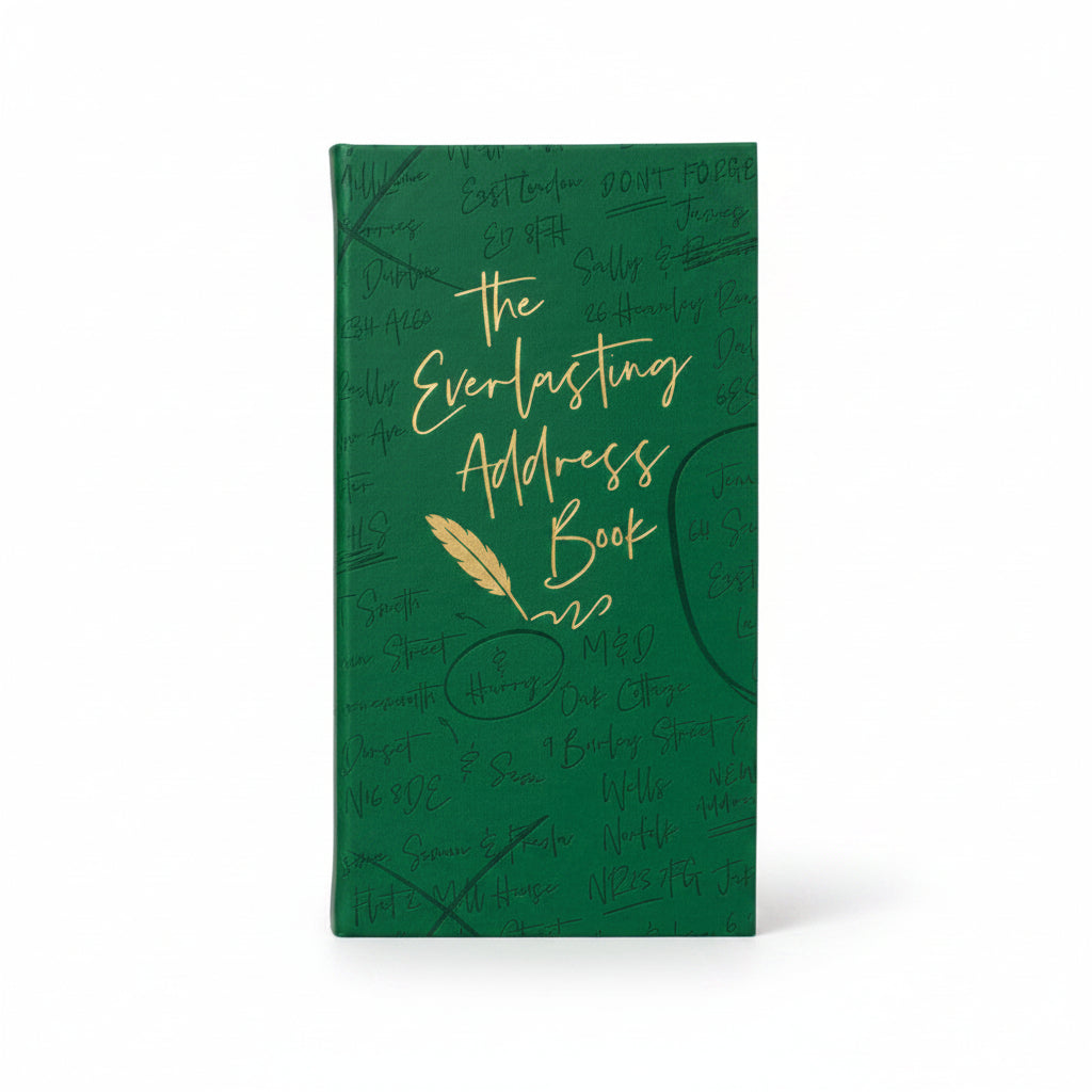 Green address book on a desk with a gold pen and notepaper