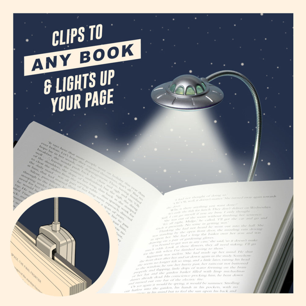 UFO book light clipped to an open book, lighting up the page