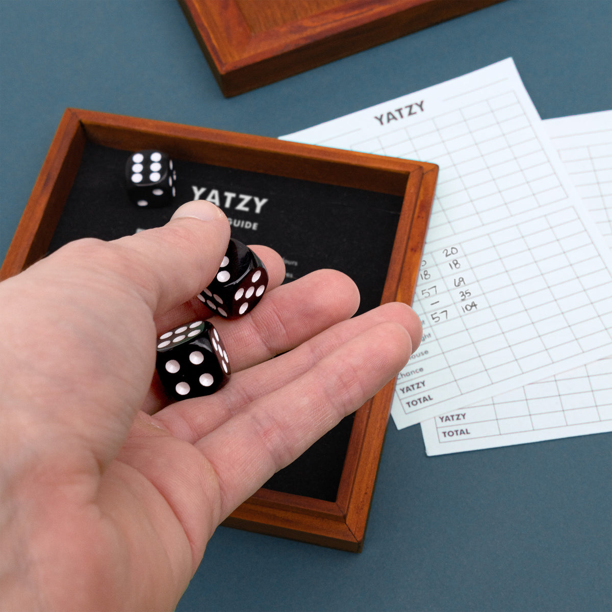 Hand rolling black dice into the Iron & Glory Yatzy wooden tray