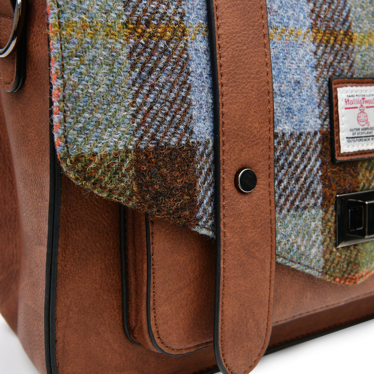 Close-up of the Harris Tweed authentication label and clasp on the Islander Chestnut & Blue Tartan Satchel.