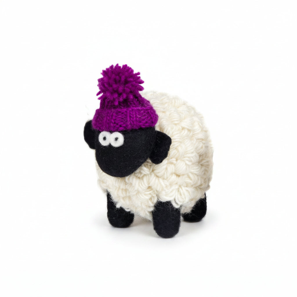 Hand-knitted wool sheep figure wearing a purple bobble hat