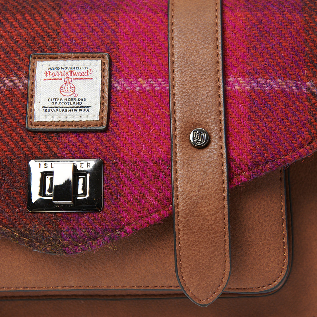 Close-up of Fuchsia Red Tartan Harris Tweed® satchel highlighting woven texture, Harris Tweed® label, and tan leather trim.