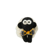 Knitted wool sheep keyring wearing a yellow tartan bowtie, on a plain white background.