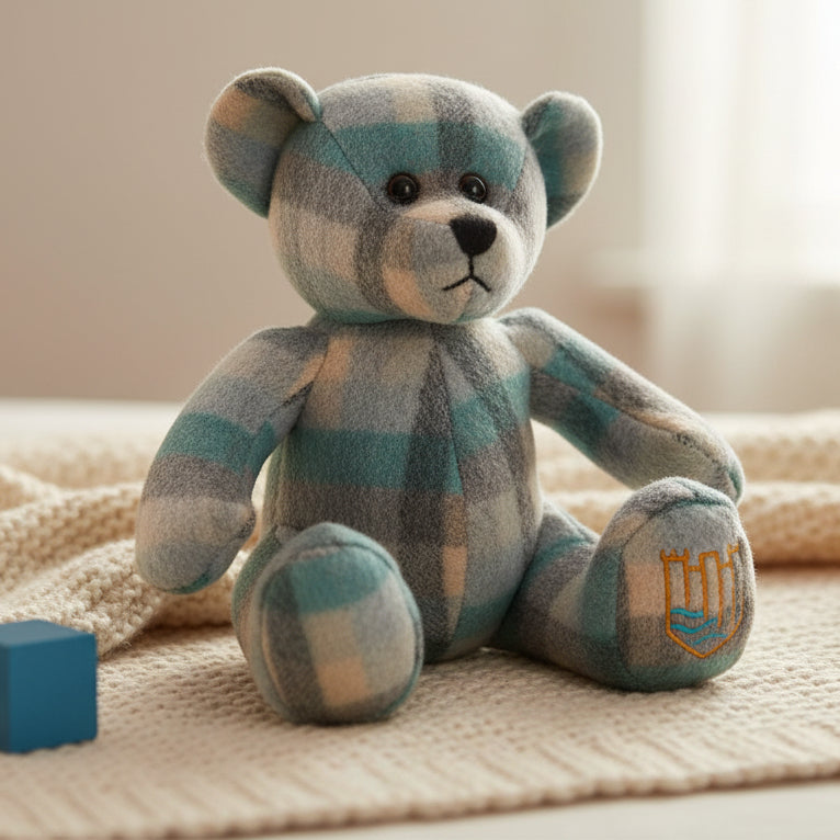 Lambswool teddy in teal Islander tartan on cream blanket with wooden block.