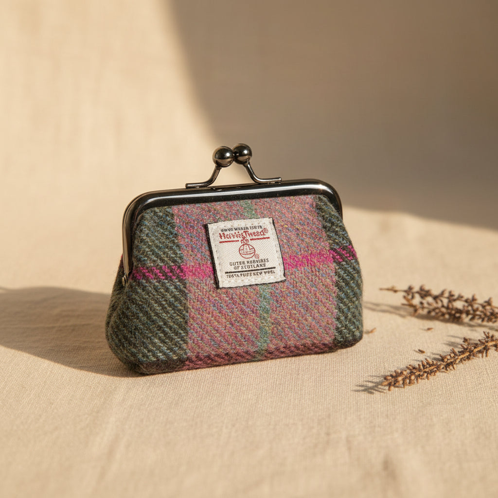 A small Harris Tweed kiss-lock coin purse in a pink, blue, and green plaid pattern, featuring a white brand label on the front and a dark metal kiss-lock clasp.