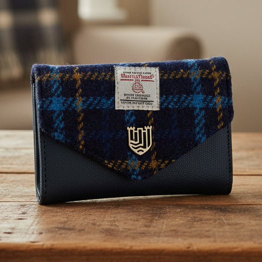 Navy tartan Harris Tweed clasp purse with teal leather on wooden surface.
