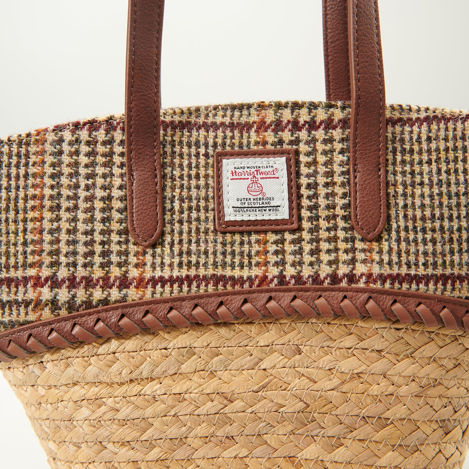 Close up of the dogtooth Harris Tweed lid, plaited leather trim and label