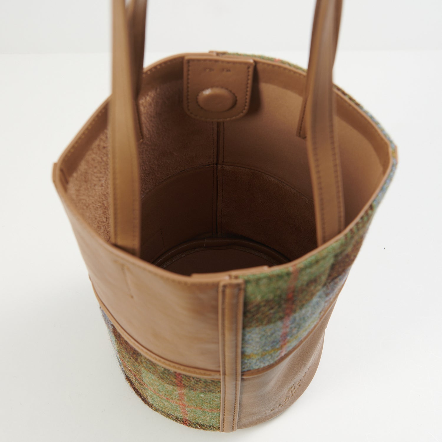 Interior button closure detail on chestnut-blue tartan bucket bag