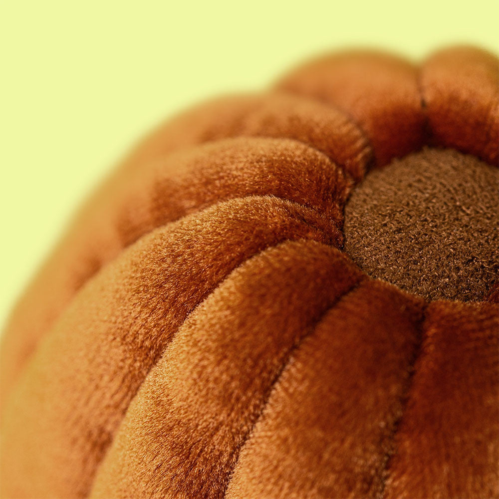 Close-up of velvet ridged canele pastry texture on cream background