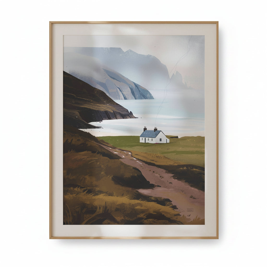 A framed landscape art print depicting a small white cottage on a grassy hill overlooking a misty sea and dramatic mountains, presented in a light wood frame with a cream mat against a white background.