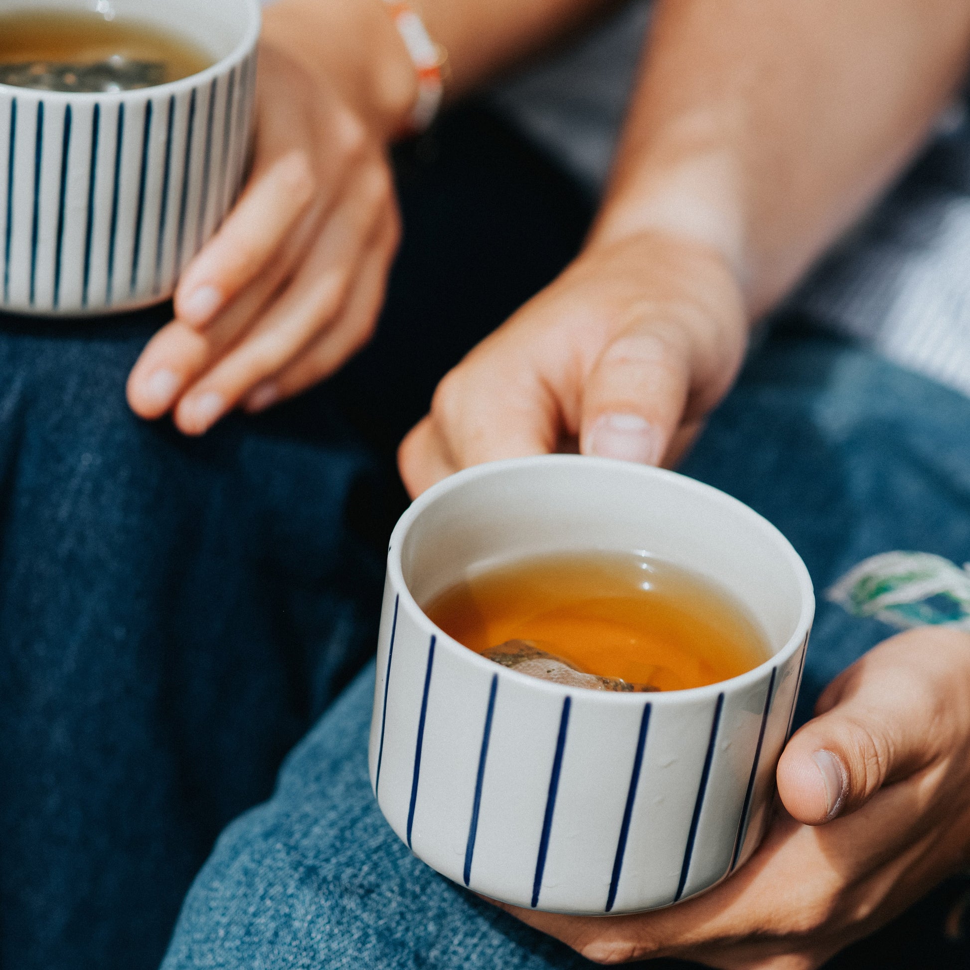Person holding an indigo blue Yarrow mug filled with tea