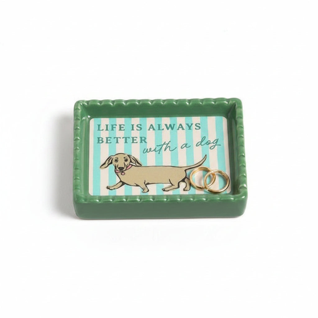 Ceramic trinket dish with dachshund design and striped background holding gold earrings.