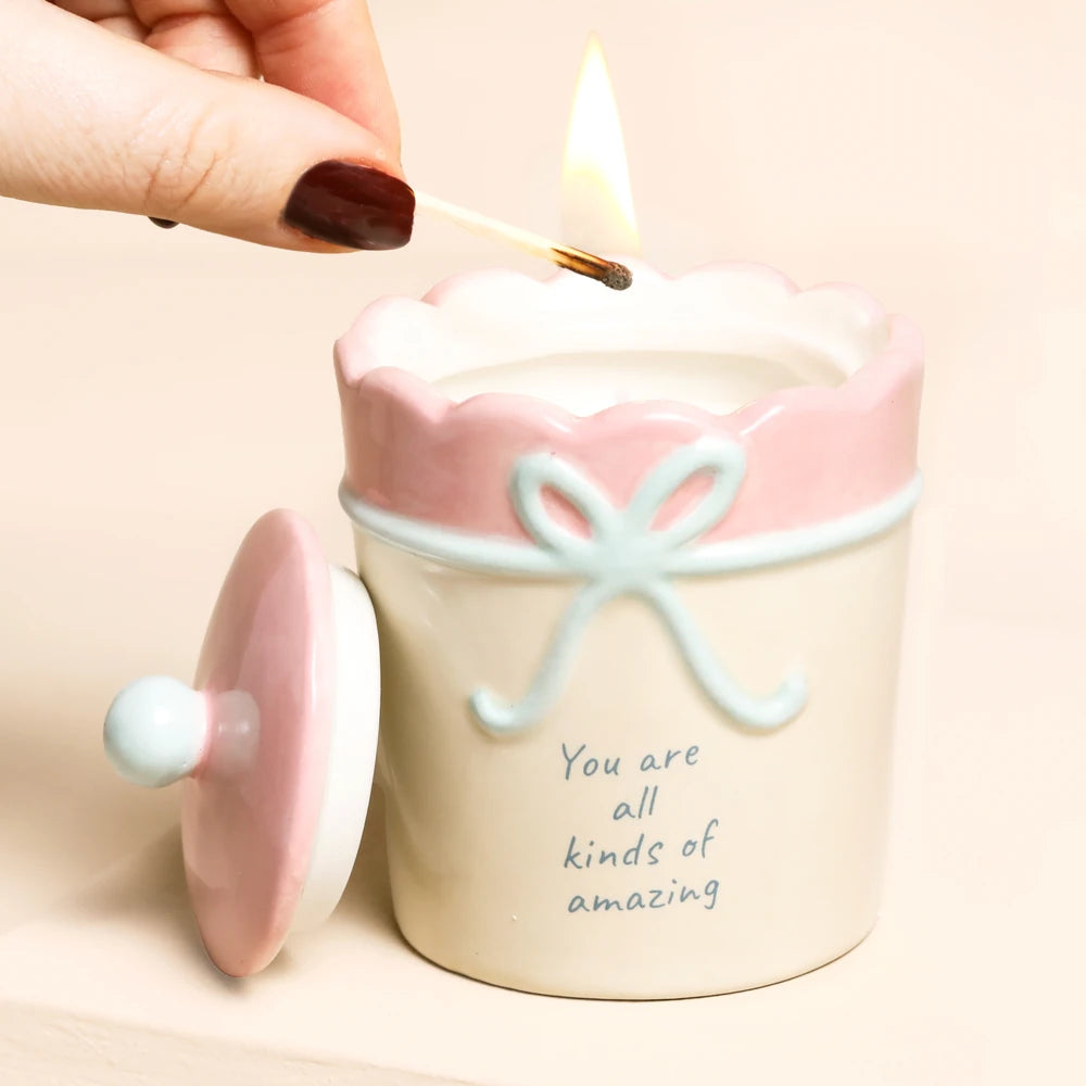 Hand lighting the candle with a match, pink lid resting alongside