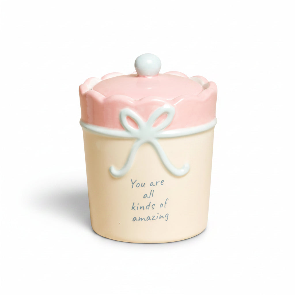 Cream ceramic candle with pink scalloped lid and blue bow, lid on
