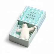 White ceramic bear token with open arms in blue striped matchbox