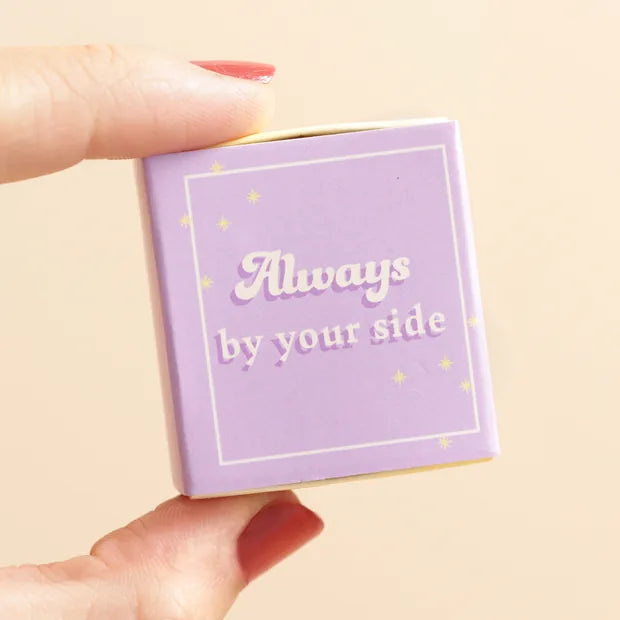 Hand holding closed lilac matchbox with star design on cream background
