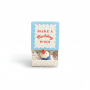 Ceramic cupcake inside open confetti matchbox with blue lid on cream background
