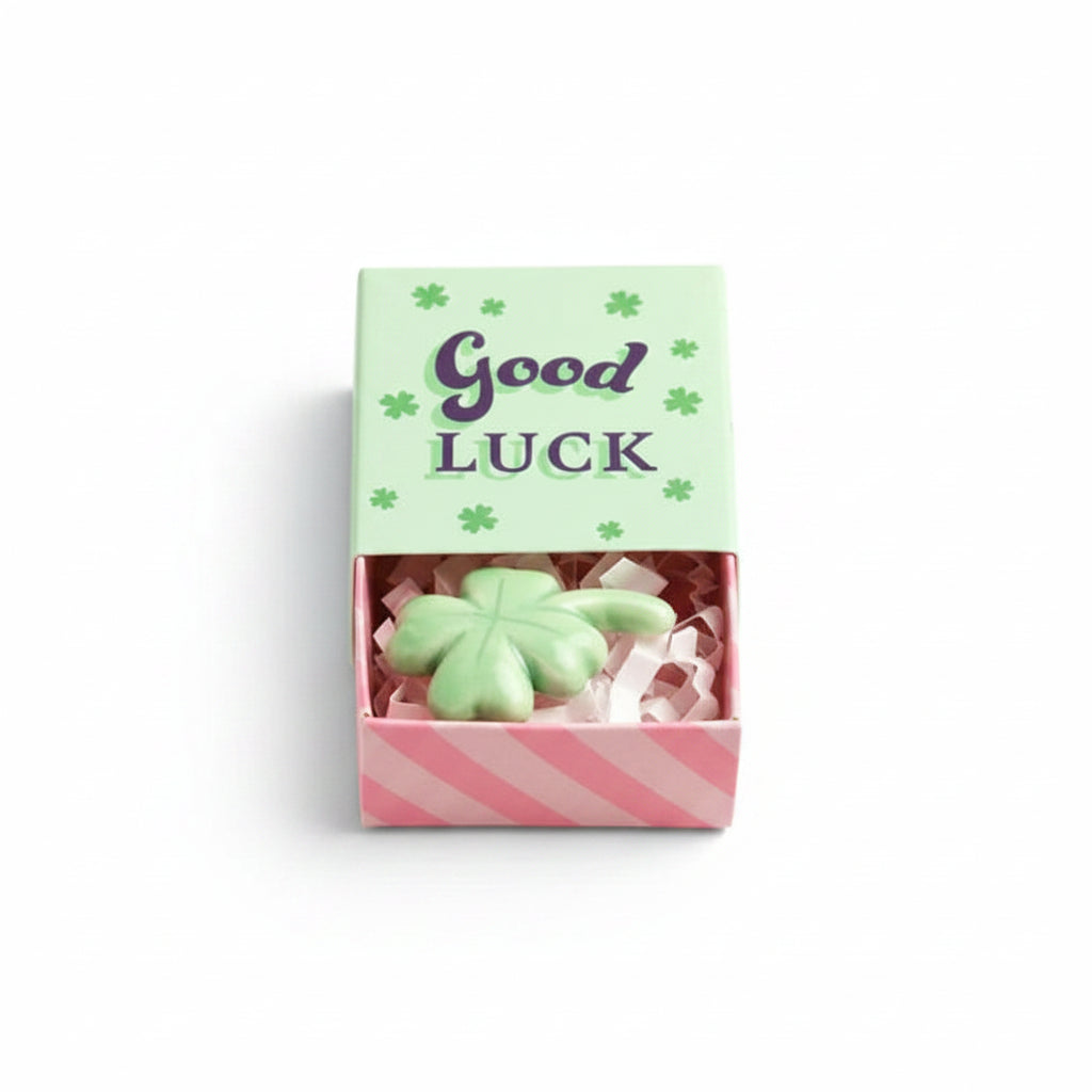 Green ceramic clover inside open matchbox with mint green lid on cream background