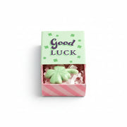 Green ceramic clover inside open matchbox with mint green lid on cream background