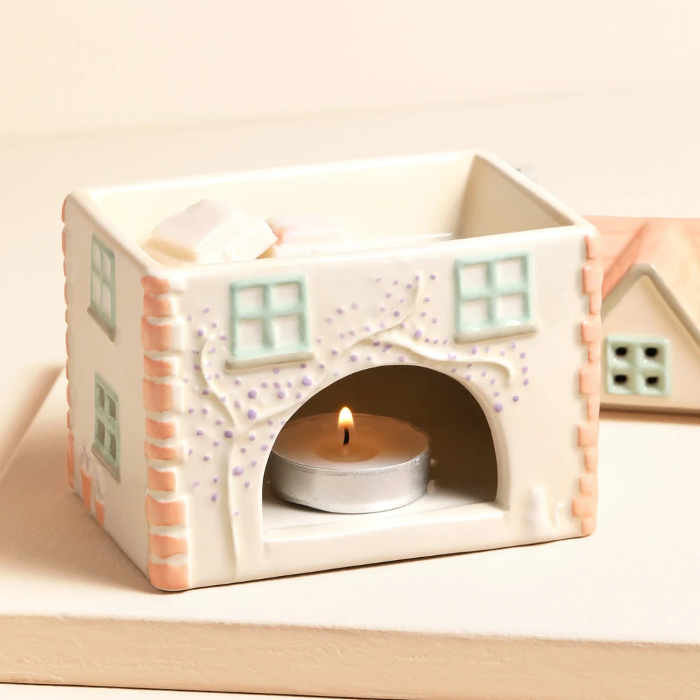 Cottage wax burner styled on a wooden shelf beside trailing greenery