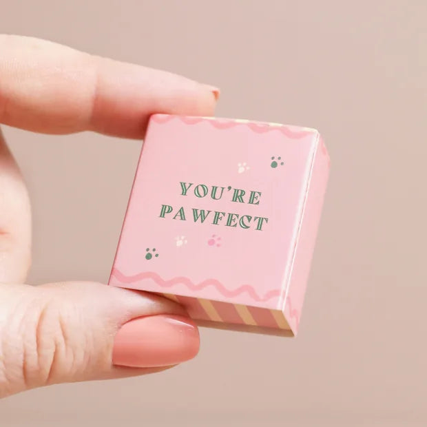 Closed pink matchbox held in fingers showing playful message