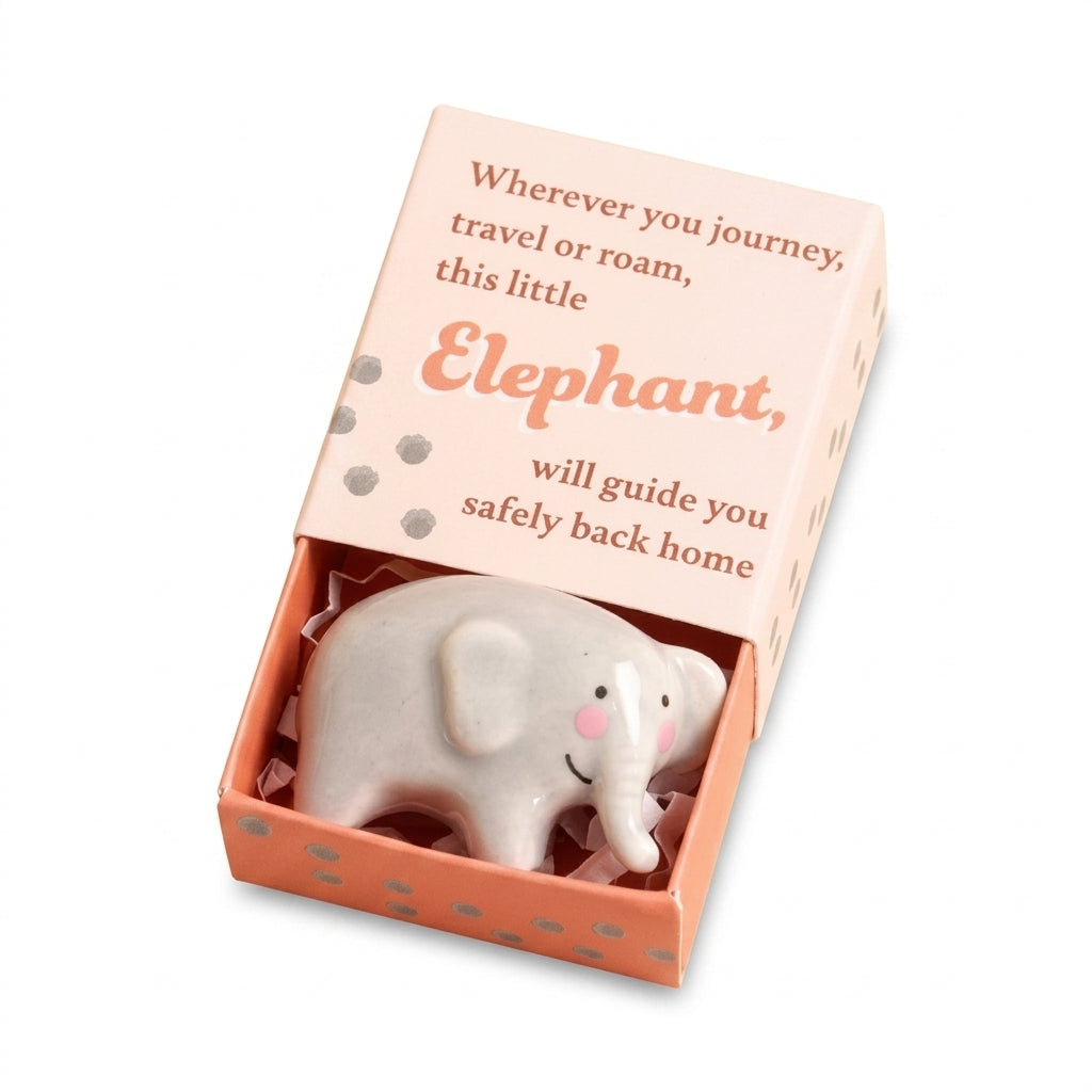 Tiny ceramic elephant token in its matchbox on white