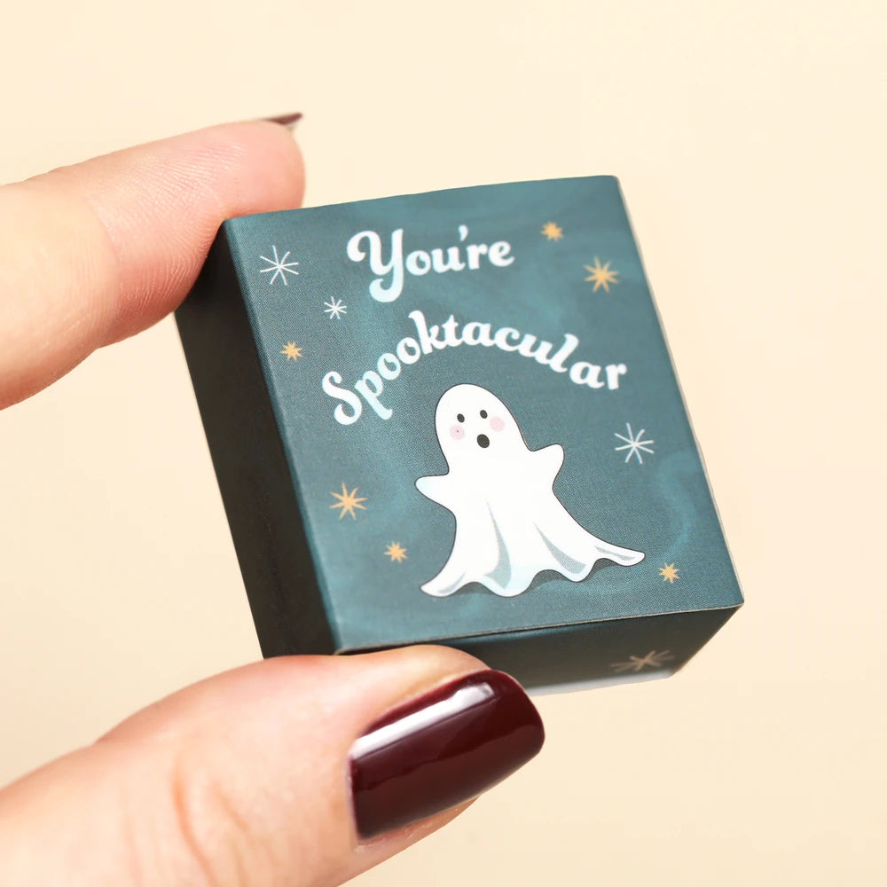 Hand holding the closed teal starry ghost matchbox for scale