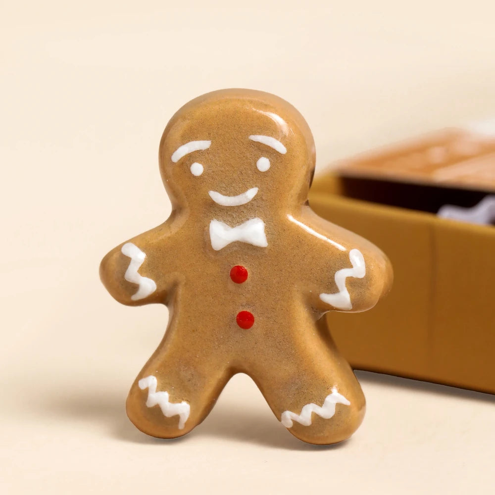 Glazed ceramic gingerbread man token with white icing and a red button