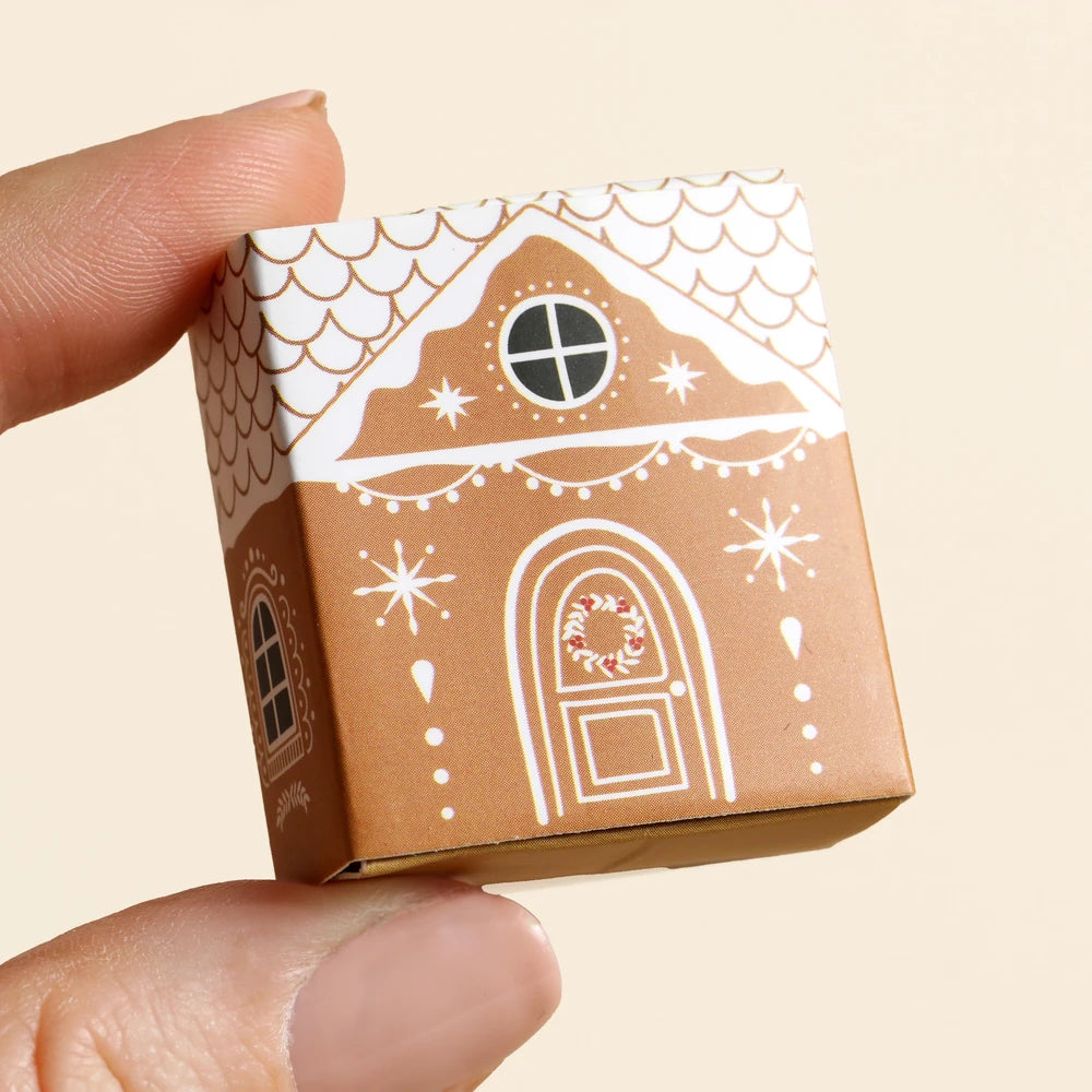 Hand holding the closed gingerbread house matchbox for scale