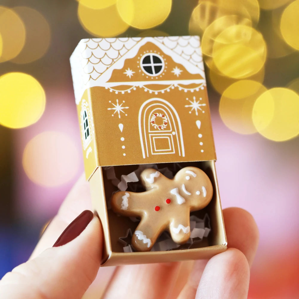 Gingerbread man matchbox token held against warm festive bokeh lights