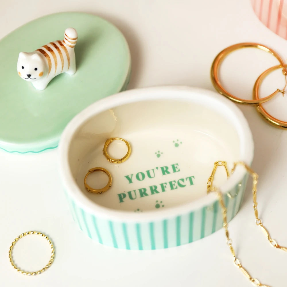 Lid lifted from the cat trinket pot showing gold rings resting inside
