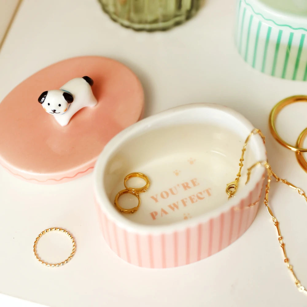 Lid lifted from the pink dog trinket pot showing gold rings inside
