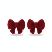 Pair of red velvet bow stud earrings resting on cream ribbed fabric