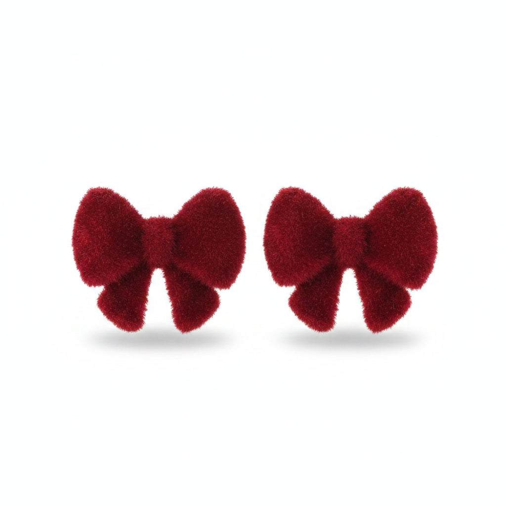 Pair of red velvet bow stud earrings resting on cream ribbed fabric