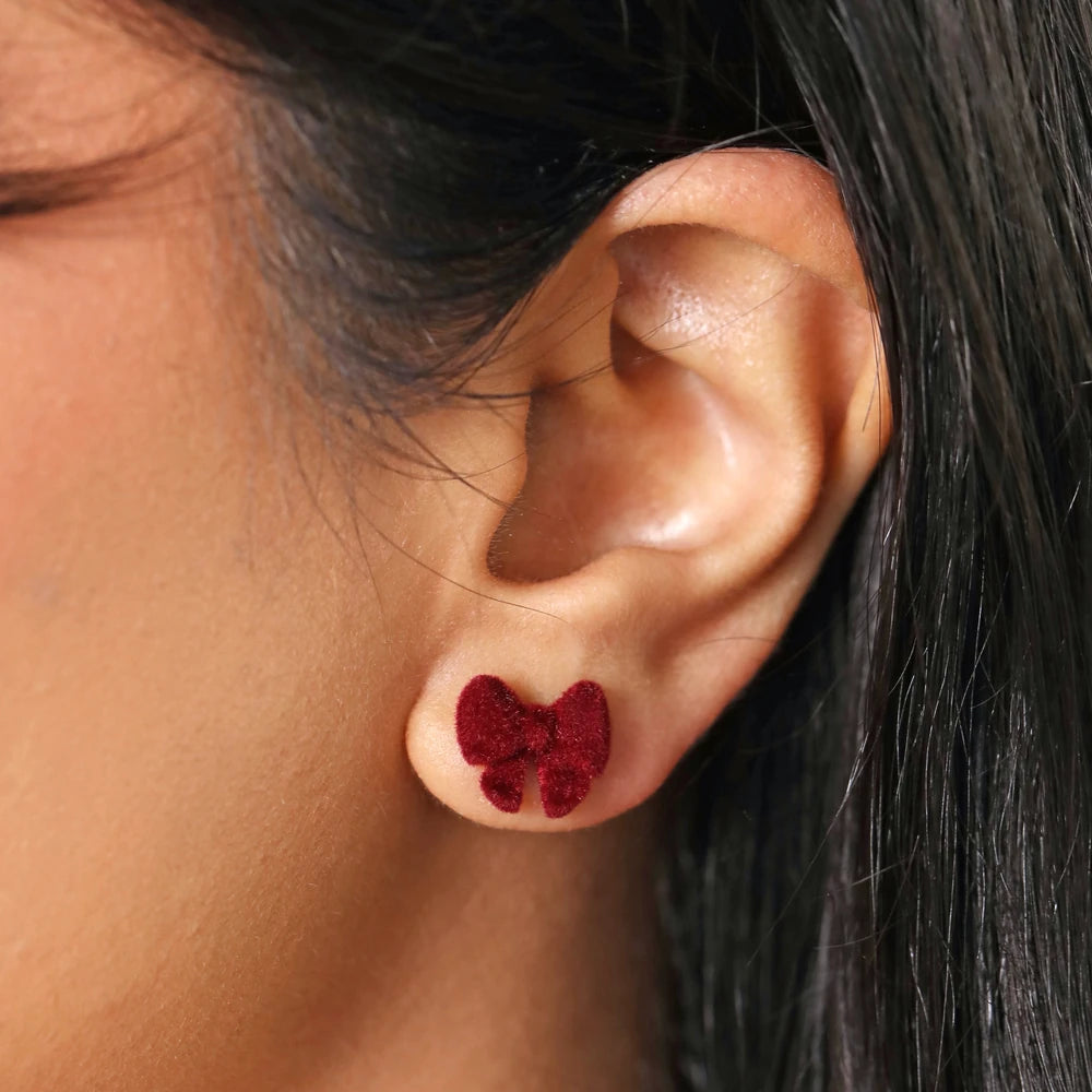 Close-up of a red velvet bow stud worn in an ear lobe