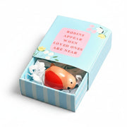 Tiny ceramic robin in blue matchbox on pink surface