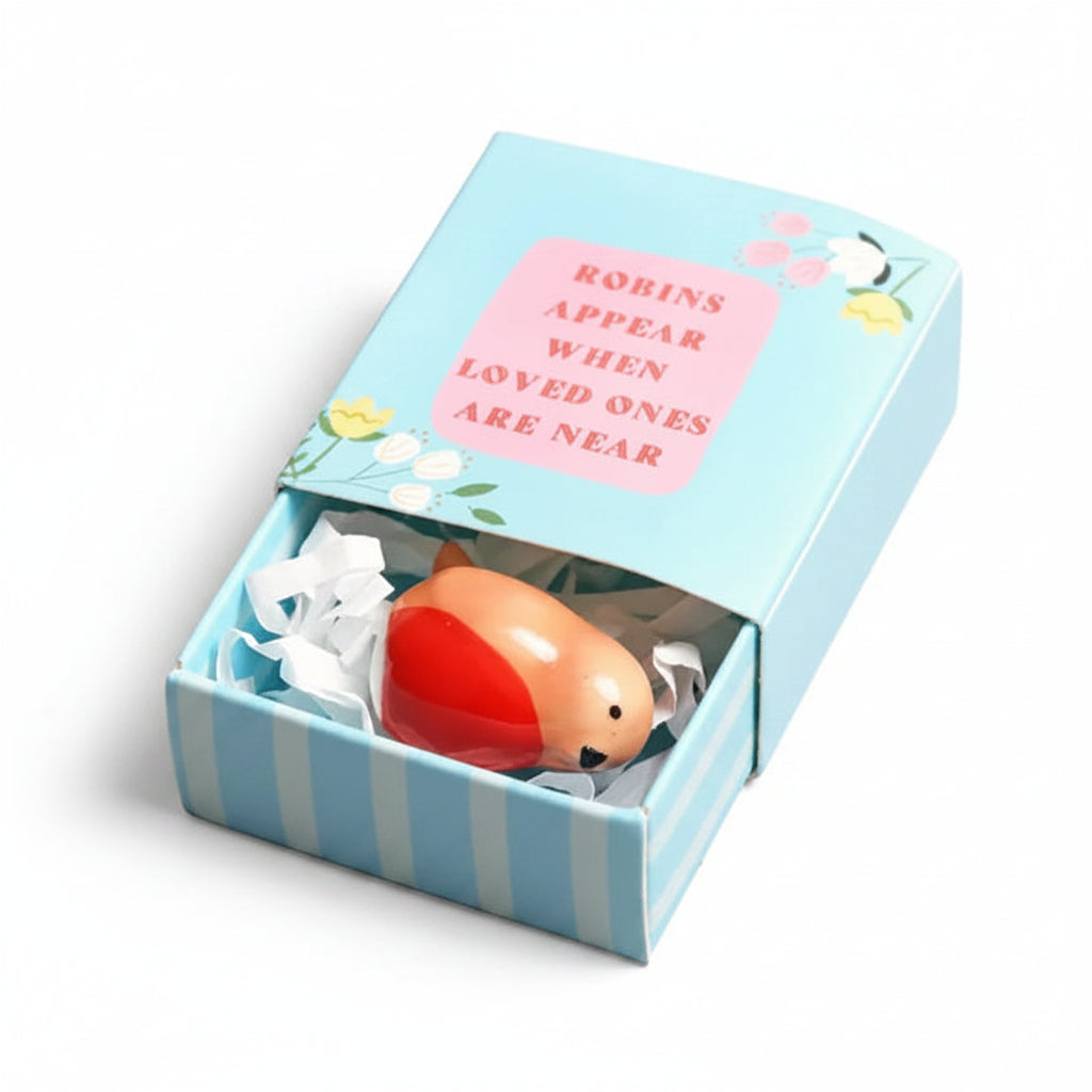 Tiny ceramic robin in blue matchbox on pink surface