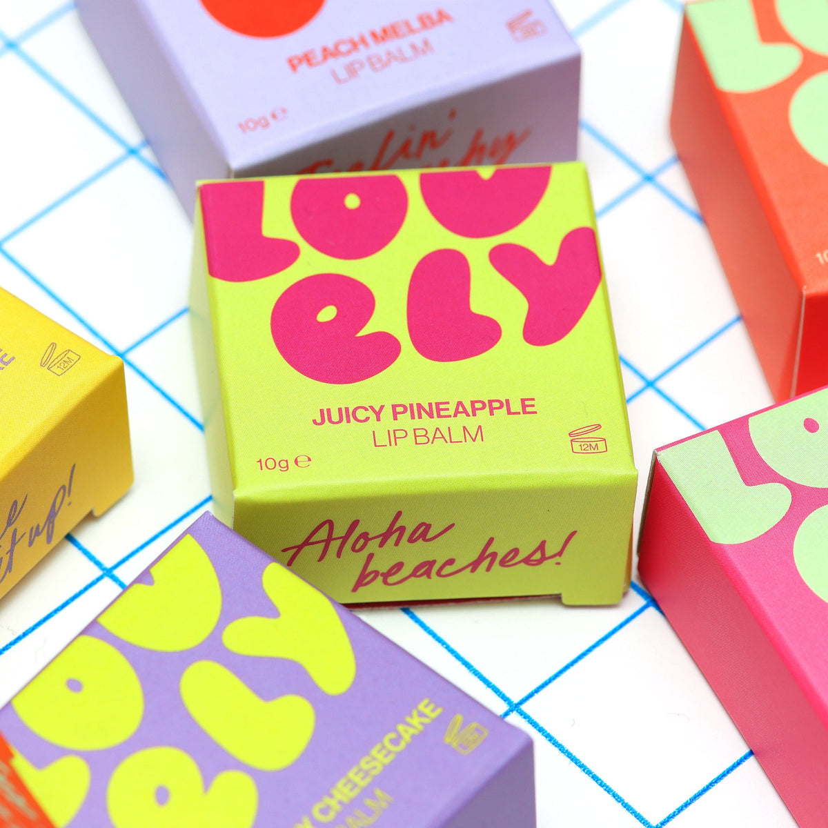Juicy Pineapple lip balm box on a blue grid