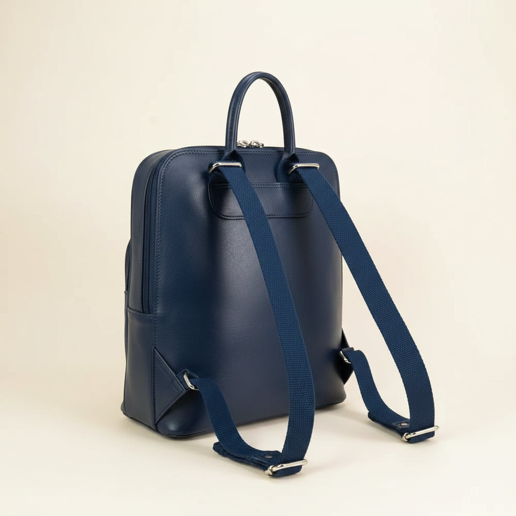 Reverse of the sky blue backpack showing the navy leather back and padded straps