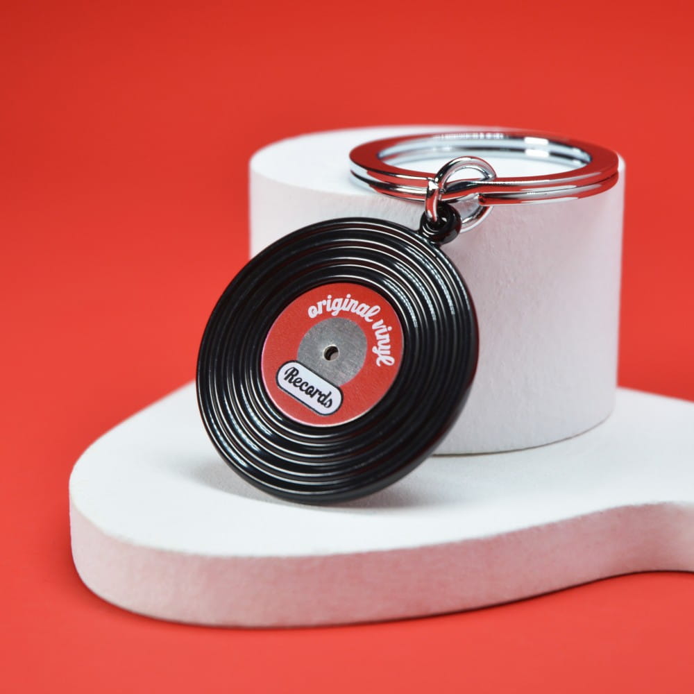 Vinyl record keyring propped against a white plinth on a red background