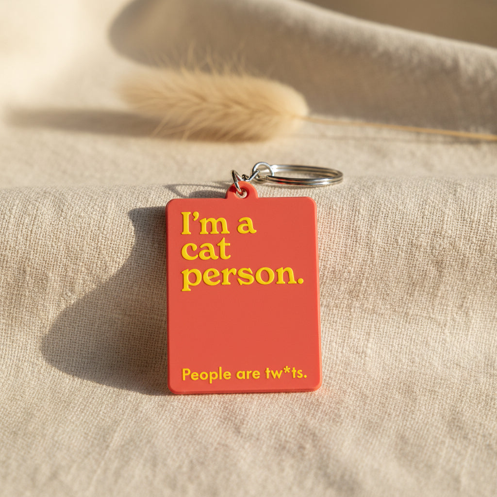Keychain with 'I'm a cat person. People are tw*ts.' text on a red background