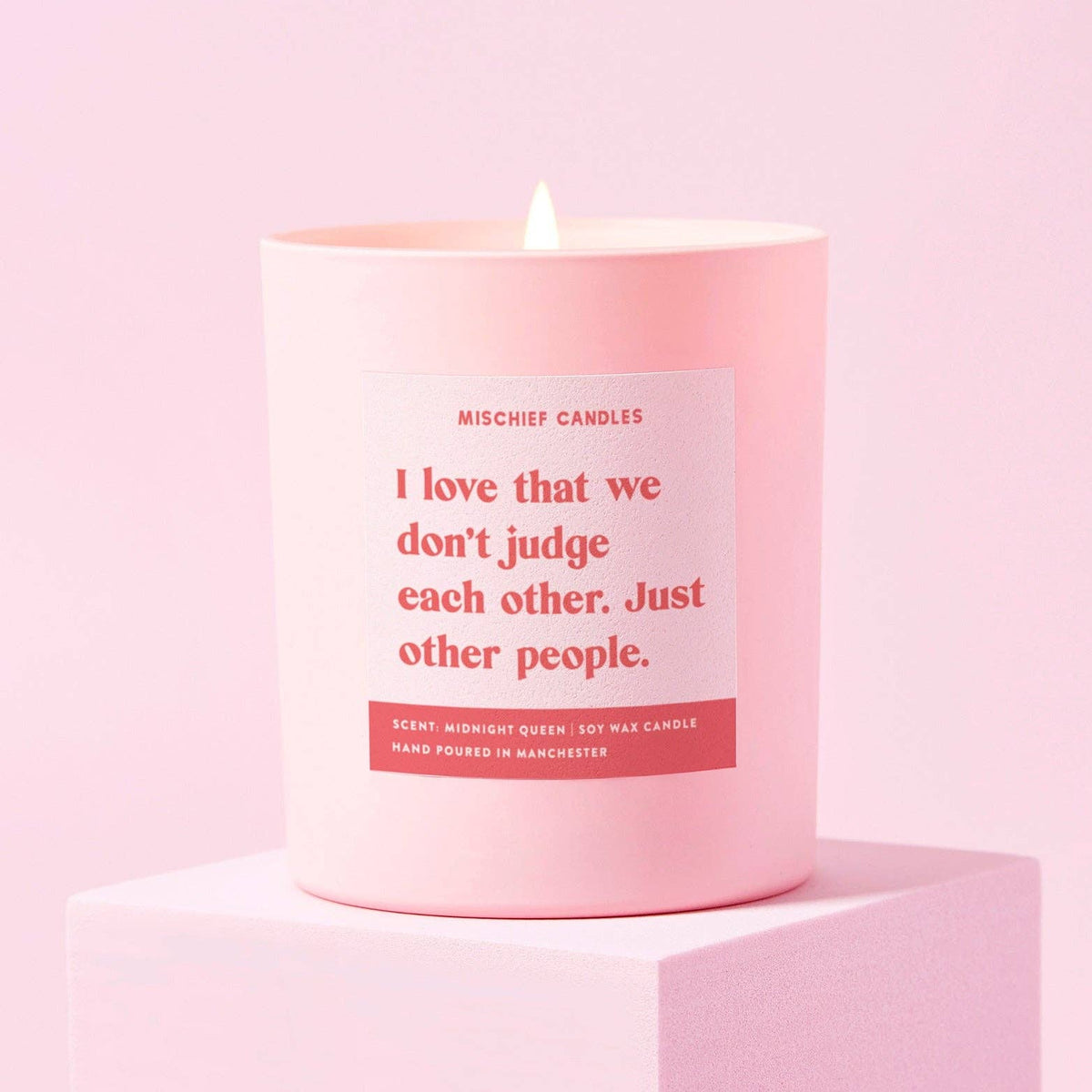 I love that we don't judge each other funny candle in a pink glass jar, lit