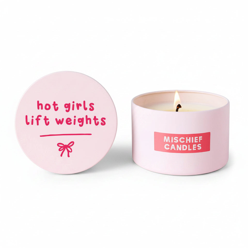 Hot Girls Lift Weights lid propped beside burning pink tin candle