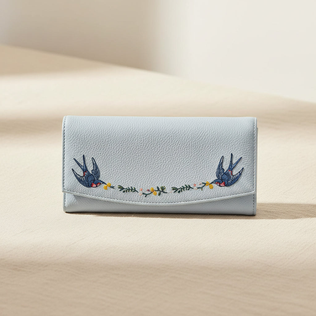 Woman holding a light blue embroidered bird purse.