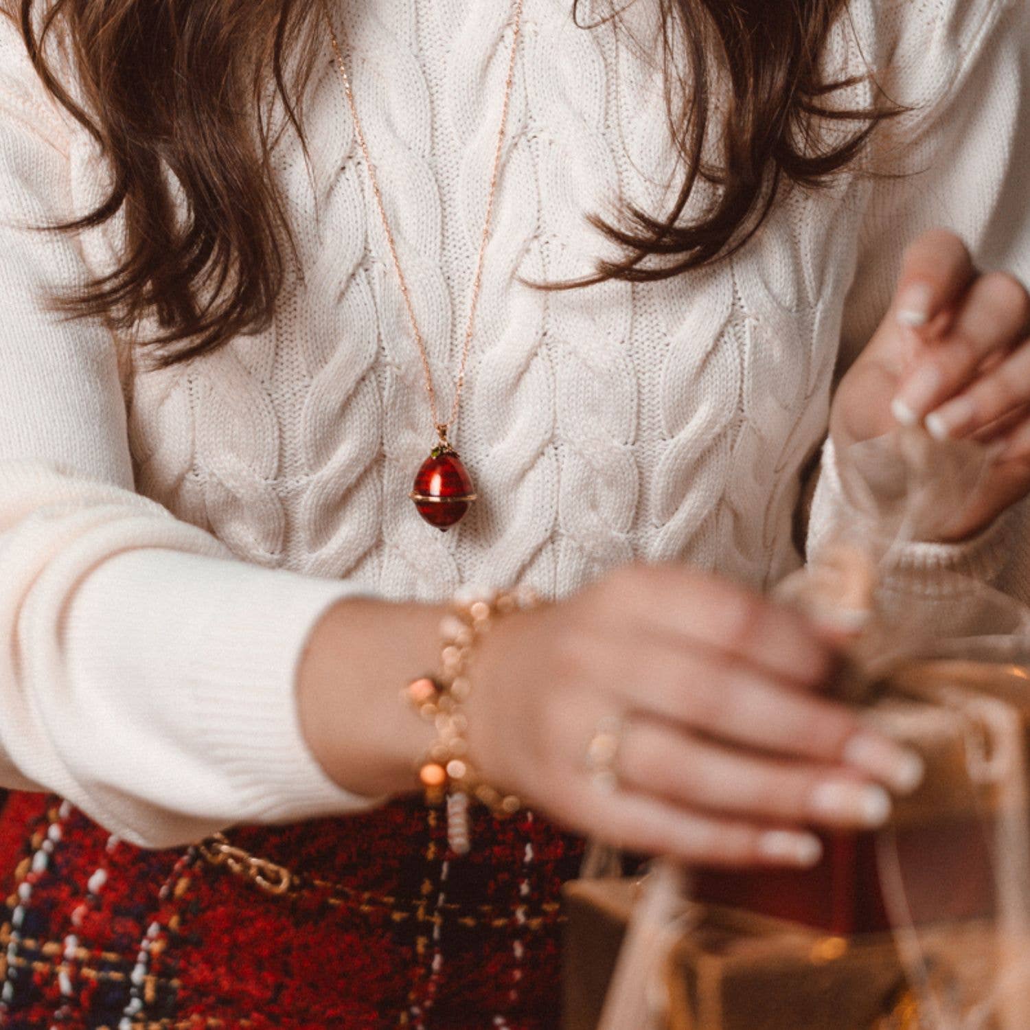 Model wearing Bill Skinner Robin Egg Locket necklace featuring red enamel egg pendant on gold chain, perfect festive jewellery gift.