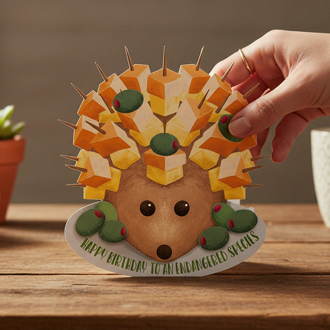 Cheese hedgehog die-cut birthday card held in hand on wooden table